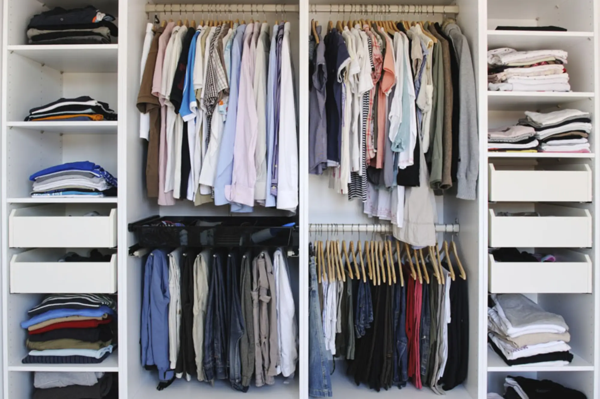 A neatly organized wardrobe featuring hanging shirts, folded clothes, and drawers displaying a variety of neatly arranged garments
